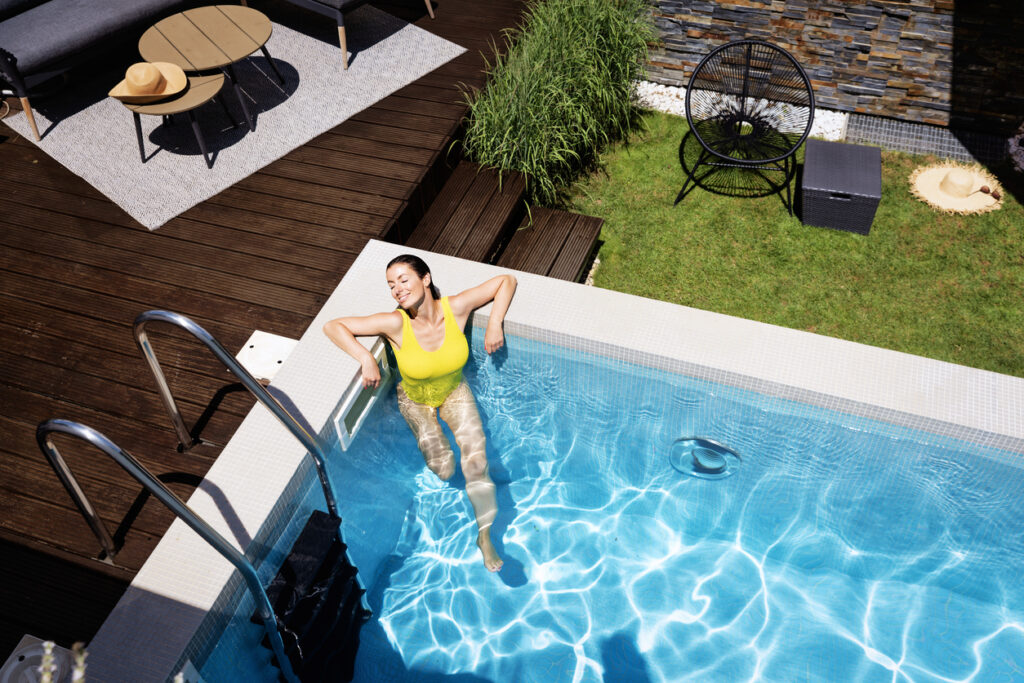 Lady relaxing in backyard pool that is clean and tidy, representing a good pool service