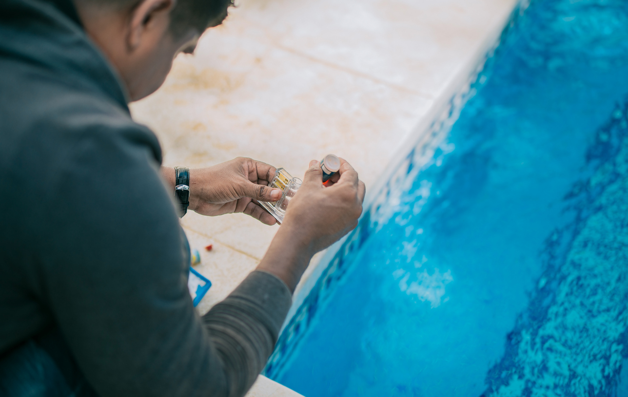 Tester kit to measure chlorine and ph in swimming pools. Person testing the PH of the pool, done by Pool Doctor expert