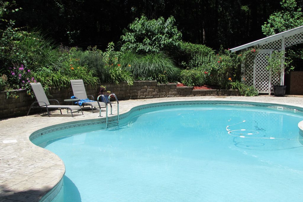 Clean backyard pool with pool chairs set in a landscaped garden, ready to enjoy.